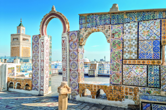 Blick durch alte B&ouml;gen mit bunten Flie&szlig;en in blau, wei&szlig;, t&uuml;rkis, im Hintergrund eine Stadt zu erkennen